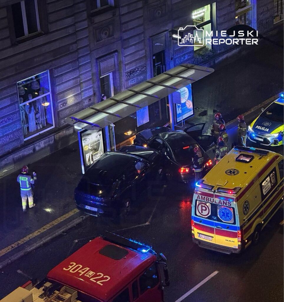 Grupa ratowników i policjantów udziela pomocy po kolizji dwóch samochodów na oświetlonej ulicy.