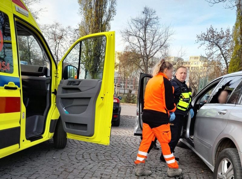 Ratownik medyczny między karetką i samochodem osobowym