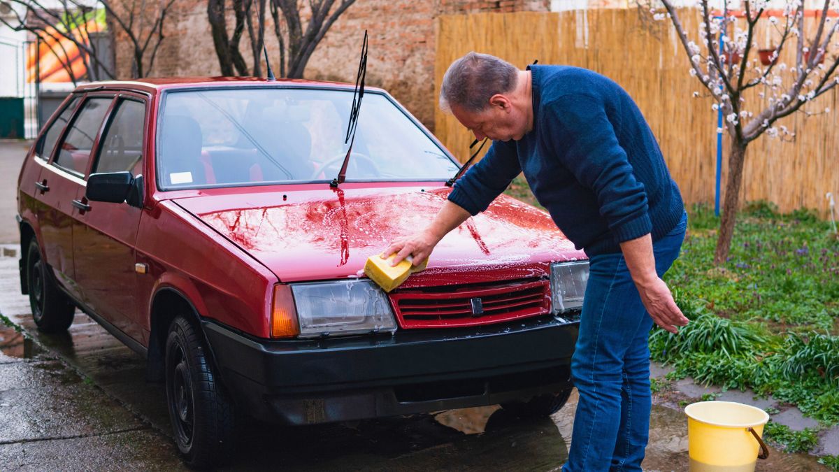 Mężczyzna myje auto na podwórku