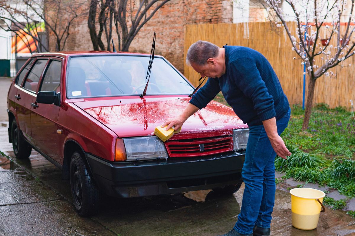 Mężczyzna myje auto na podwórku