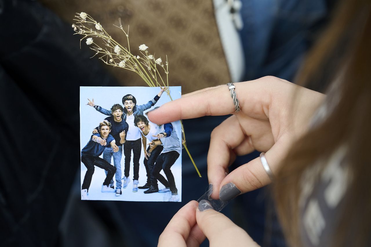 MADRID, SPAIN - OCTOBER 20: A fan holds a picture of One Direction band during a memorial gathering at Santa Ana Square on October 20, 2024 in Madrid, Spain. According to the Buenos Aires police department, Payne fell from a third-floor hotel room balcony in Palermo, a famous neighborhood in Buenos Aires. Fans around the city gather to pay tribute to the former member of boy band One Direction. (Photo by Borja B. Hojas/Getty Images)