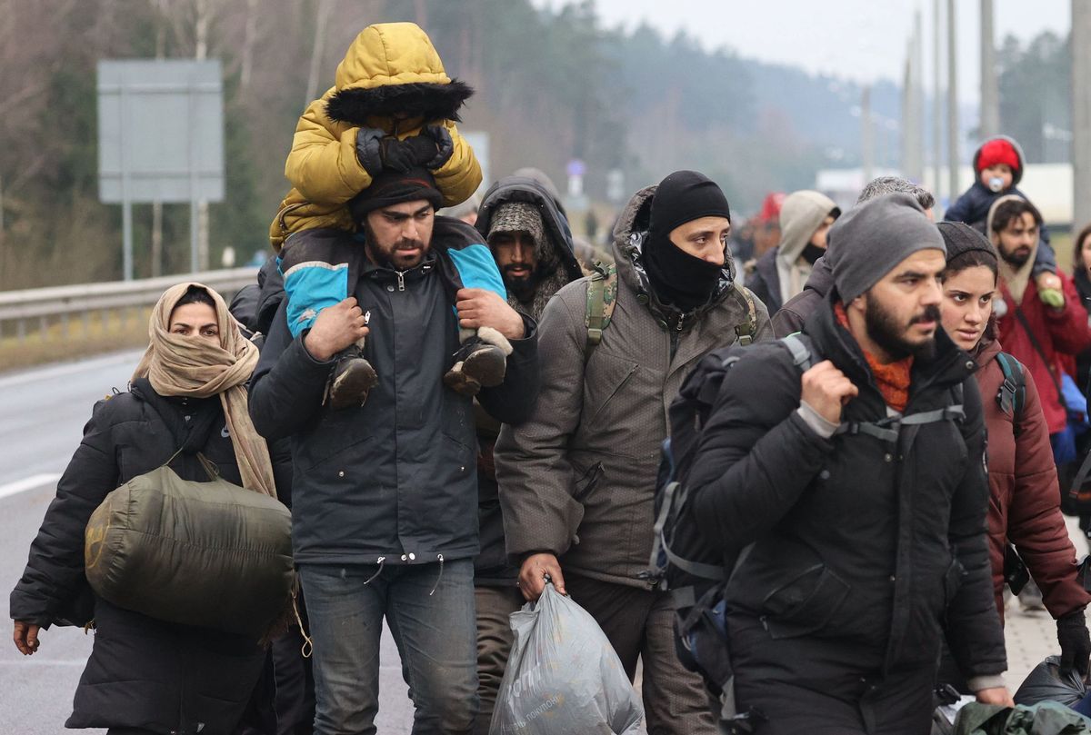 Migranci w drodze do hali magazynowej przekształconej w ośrodek tymczasowy w pobliżu przejścia granicznego w Bruzgach 