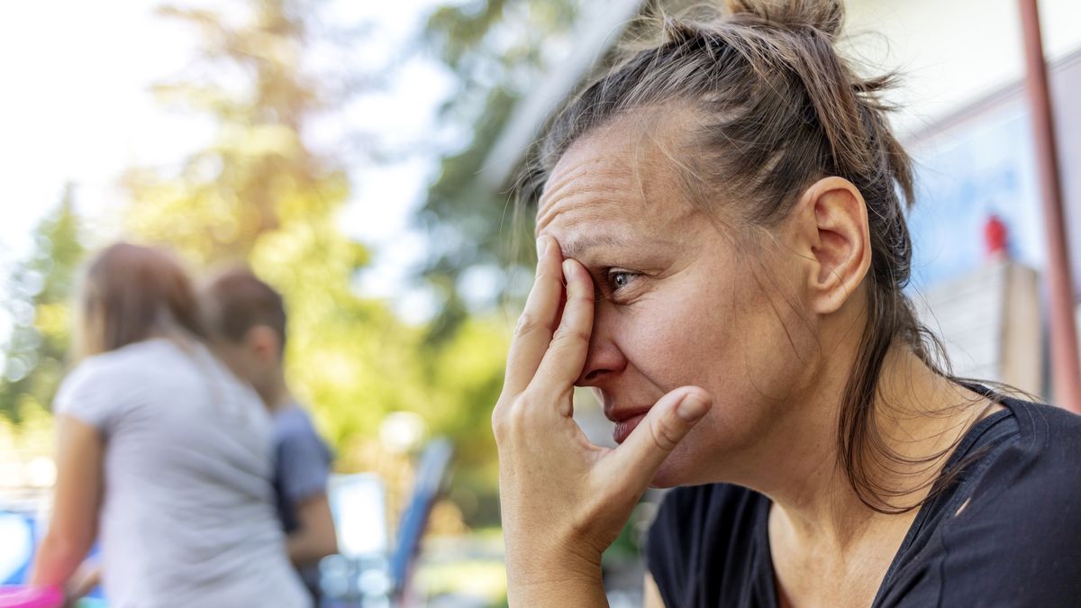 Stressed depressed young mother sits outside in a playground with her kids playing behind her.
Stressed depressed young mother sits outside in a playground with her kids playing behind her. Single frustrated woman hold her head with hands sitting on chair with playful kids on a background.
Jelena Stanojkovic