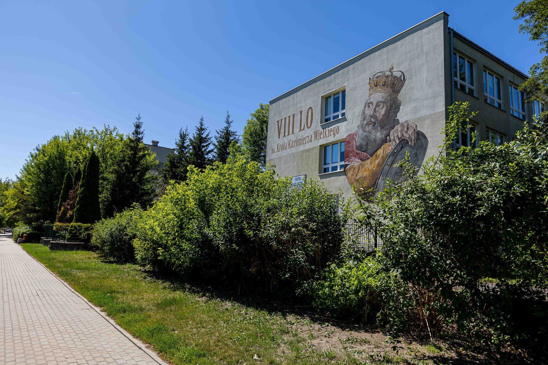 Ulica PIastowska. Na gmachu VIII Liceum Ogólnokształcącego znajdziemy mural z Kazimierzem Wielkim na bazie wizerunku króla pędzla Marcello Bacciarellego. Stojący po sąsiedzku blok przy Piastowskiej 3 to z kolei budynek zaprojektowany przez inżyniera Władysława Bacciarellego. Nadworny malarz Stanisława Augusta Poniatowskiego był jego przodkiem.