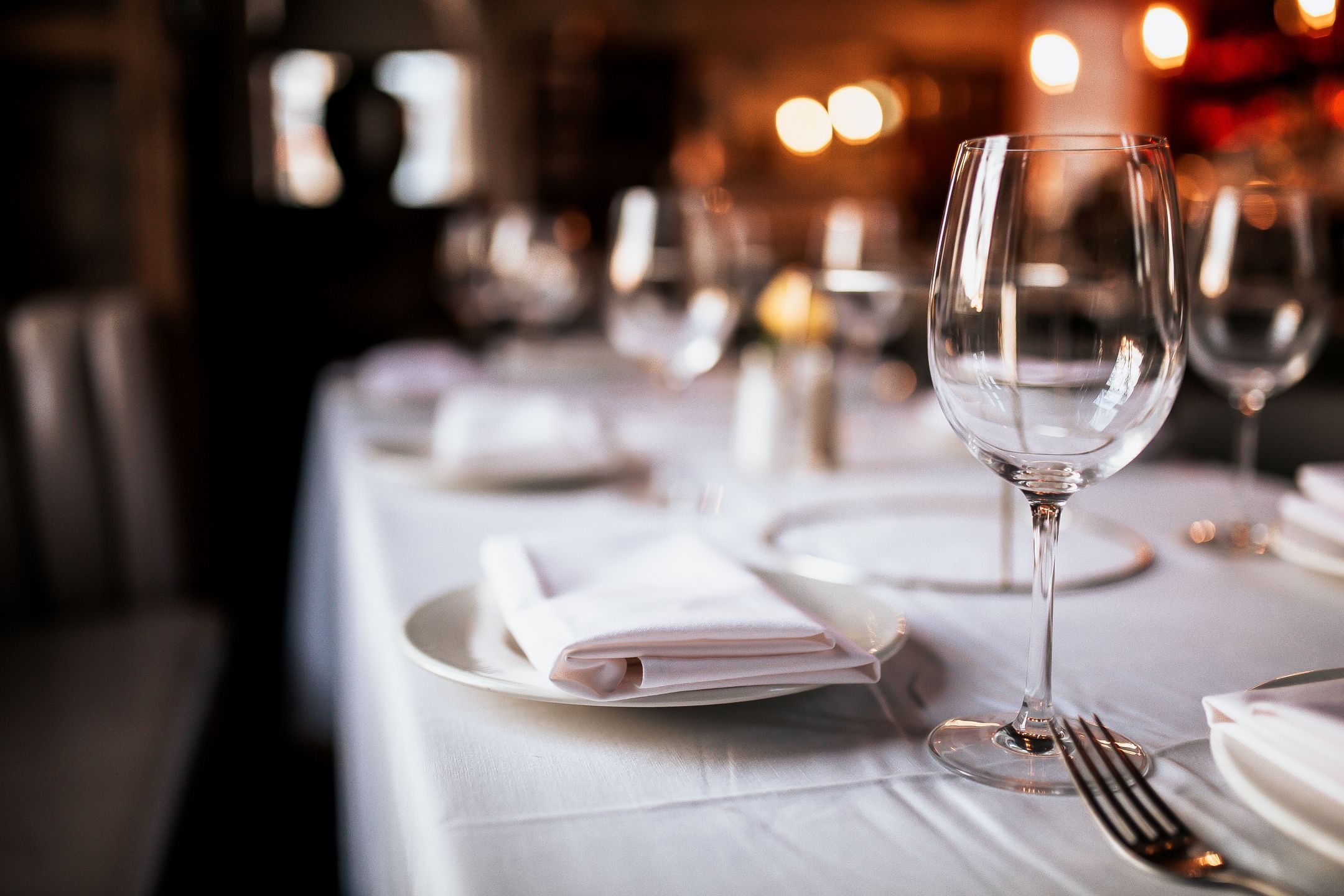 A close up shot of a restaurant table set up with tableware and wine glass. Concept of dining, hospitality and catering. Horizontal image with free space for text.
dinner, table, restaurant, setting, romantic, up, set, place, elegant, party, fine, cutlery, wine, menu, catering, white, gold, luxury, evening, glass, silverware, hospitality, glasses, wine glasses, napkins, tableware, eating, dining, service, event, table set up, copy space, space for text, background, restaurant concept, luxurious, private dinner, corporate dinner, corporate event, nobody, reflection, reserved, reservation, booking, elegance, romantic, valentines, indoors, dining area.