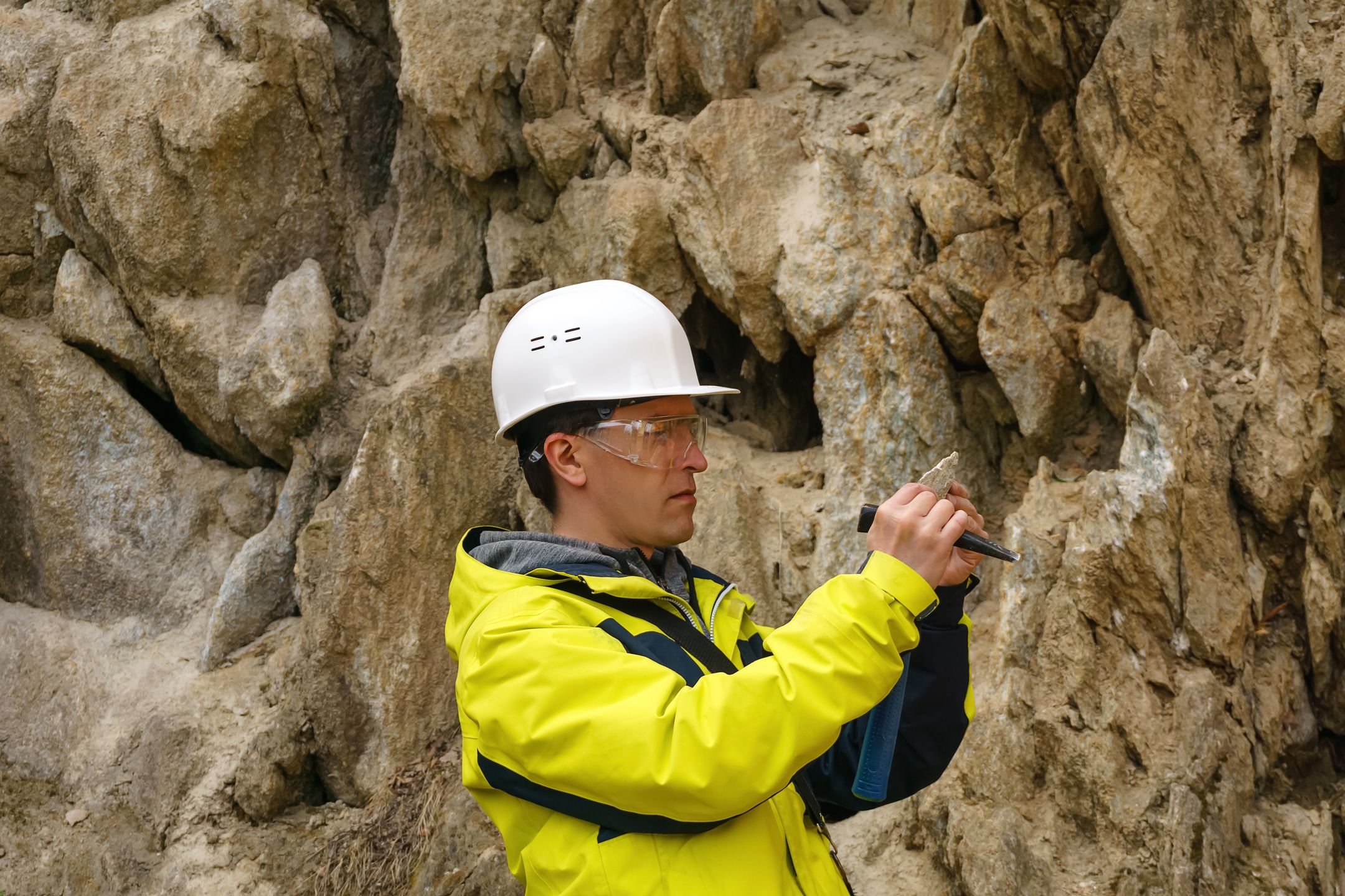 geologist examines a sample of stone outdoormale geologist in helmet and goggles examines a sample of the mineral outdoors against a rockmale, man, geologist, mineralogist, helmet, goggles, protective, glasses, examines, sample, stone, mineral, outdoors, against, rock, backround, studies, looks, satisfied, smiling, pleased, natural, nature, expedition, explorer, scientist, prospector, mining, engineer, geological, exploration, explorer, person, hammer, cliff, canyon, wall, outcrop, shard, pebble, piece, petrology, petrologist