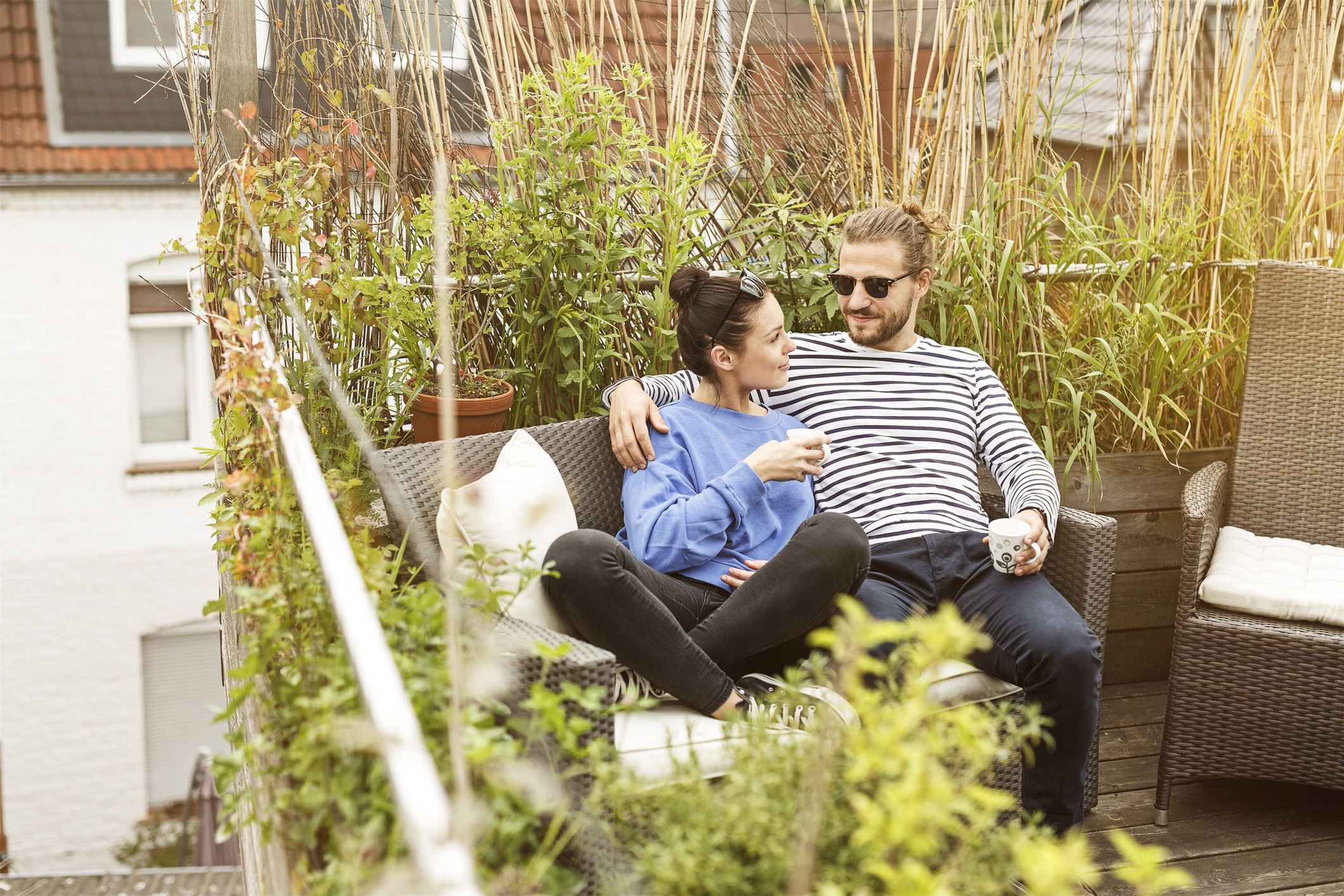 Young couple relaxing on their balcony, sitting on couchWestend61affection, casual, couple, home, leisure, quality time, recreation, relationship, terrace, woman