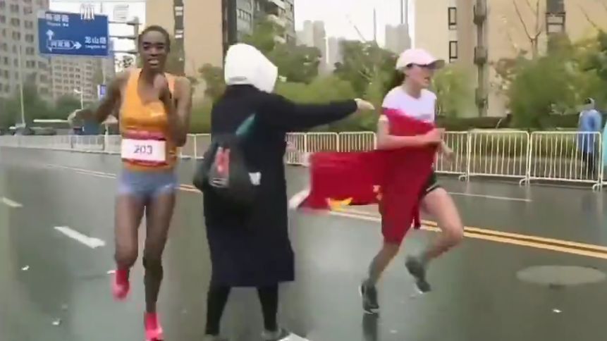 wolontariuszka wręcza chińską flagę He Yinli Obok zawodniczka z Etiopii, późniejsza zwyciężczyni maratonu w Suzhou