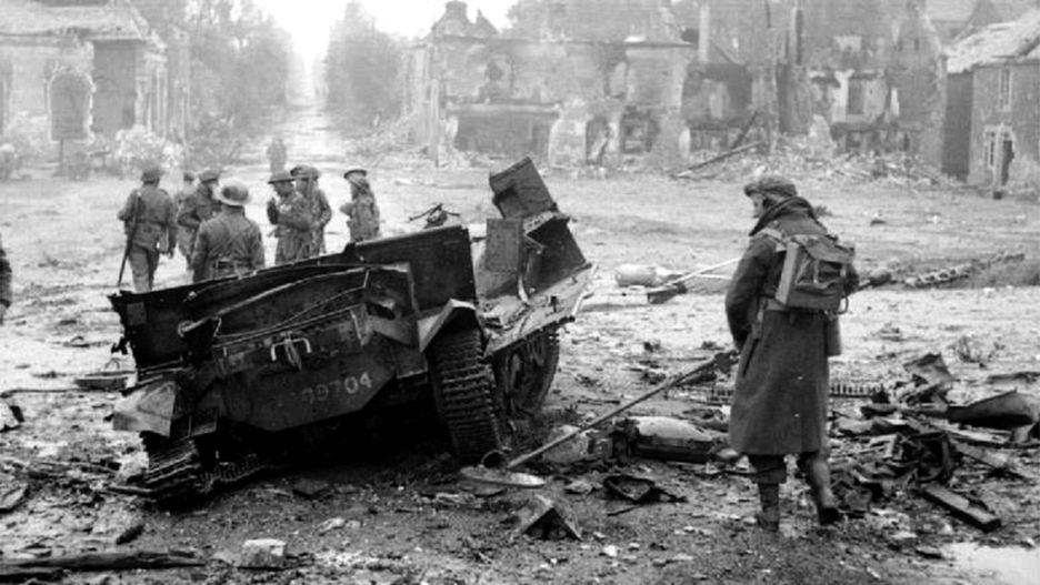 Żołnierz z "polskim" wykrywaczem min przy pojeździe wysadzonym przez minę we francuskiej miejscowości Tilly-sur-Seulles, 19 czerwca 1944 r.
