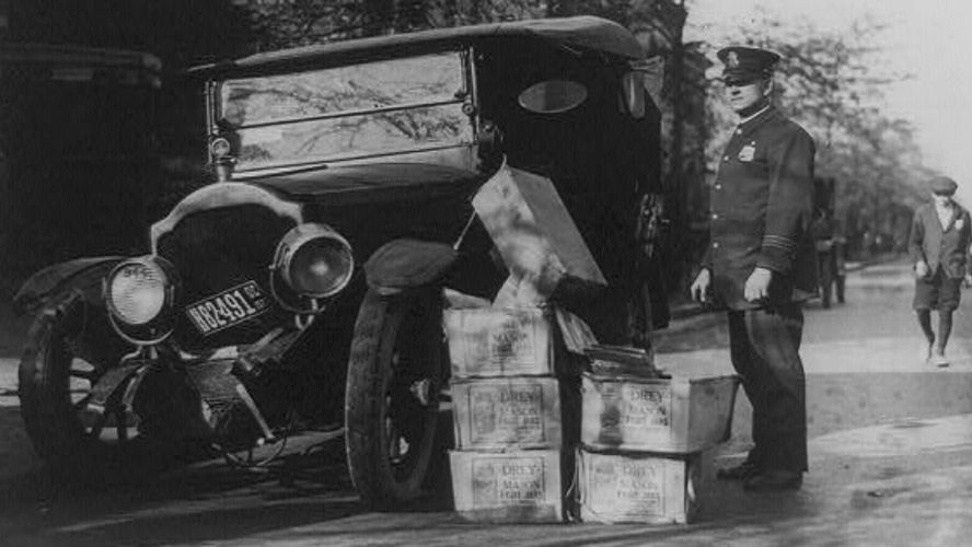 Amerykański policjant przy wraku samochodu i skrzynkach zarekwirowanego nielegalnego alkoholu, 1922 r.