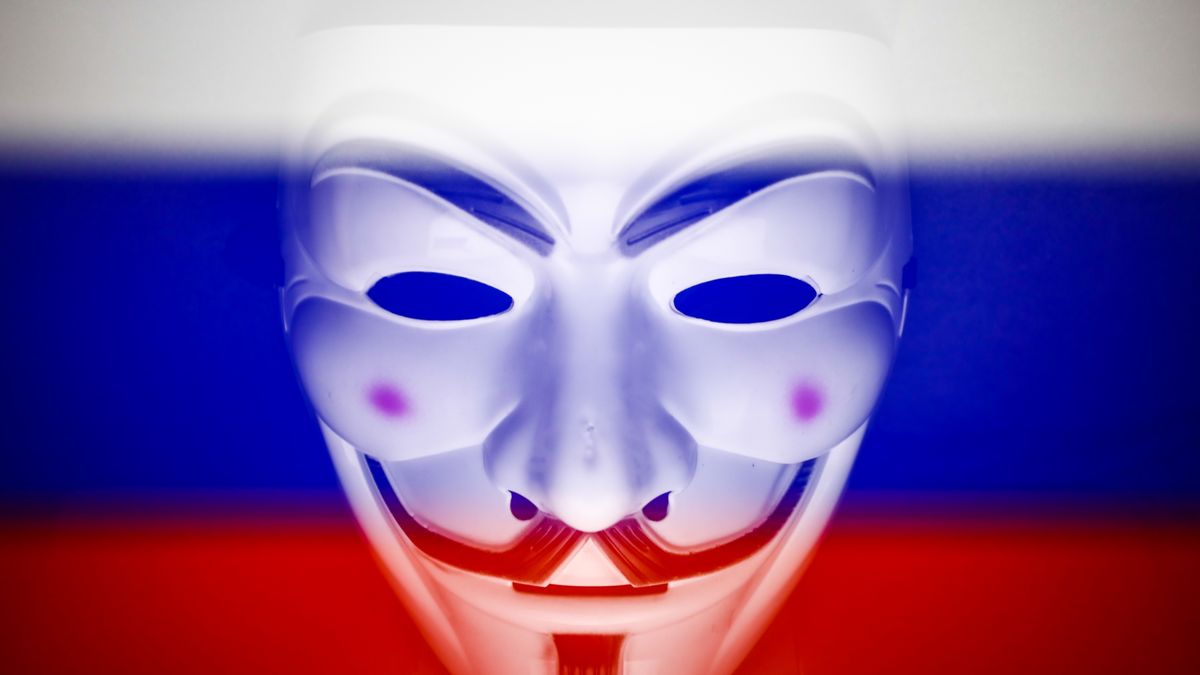 Russian flag displayed on a laptop screen and Guy Fawkes mask are seen in this multiple exposure illustration photo taken in Krakow, Poland on March 1, 2022. Global hacker group Anonymous declared 'cyber war' against Russia. (Photo by Jakub Porzycki/NurPhoto via Getty Images)