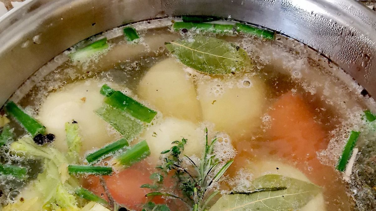 Making chicken bone brothA tall pan on the hob cooking chicken broth©Daniela White Images