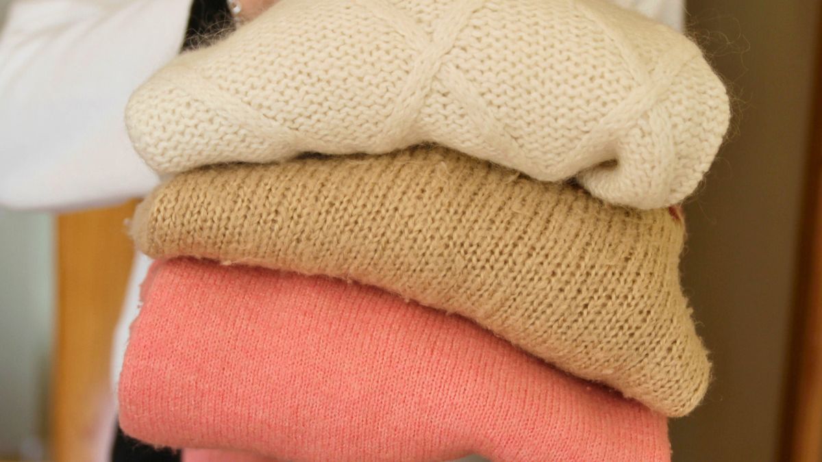 Kobieta trzyma złożone swetry
