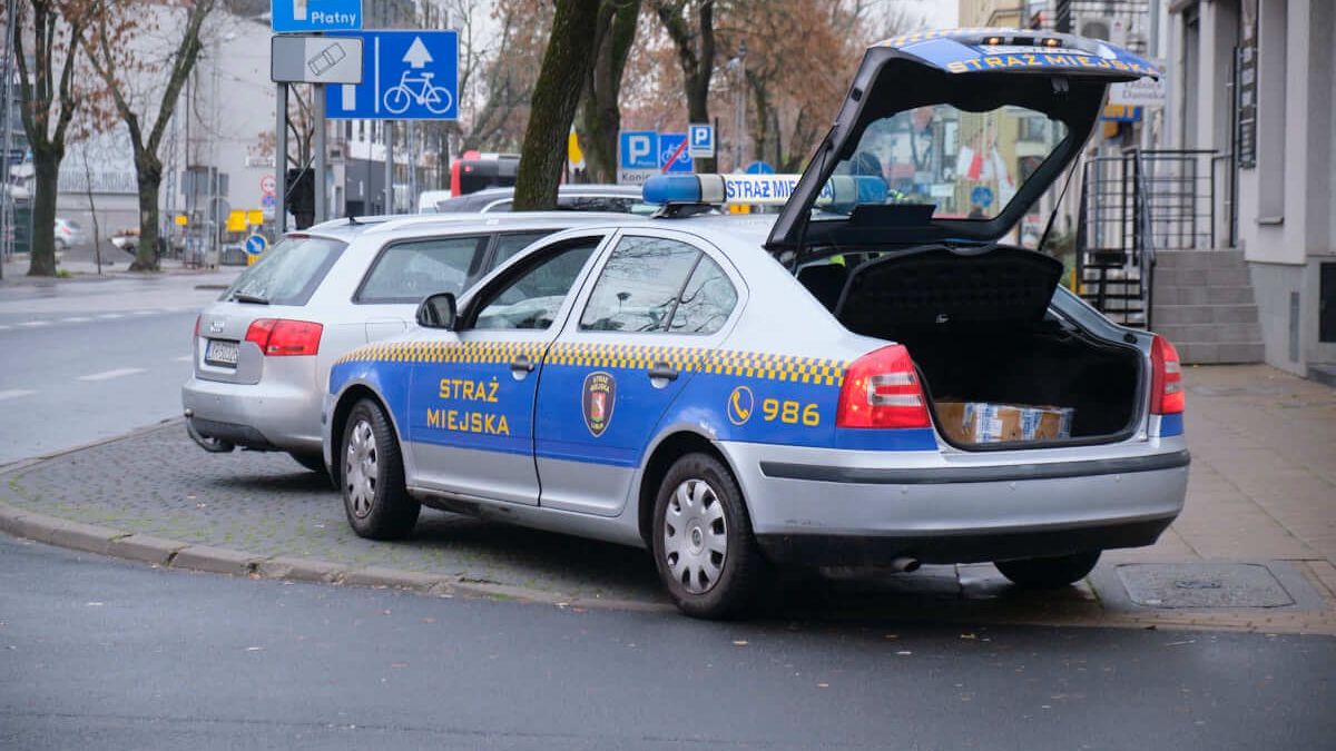 Patrol straży miejskiej zakładający blokadę na koło samochodu