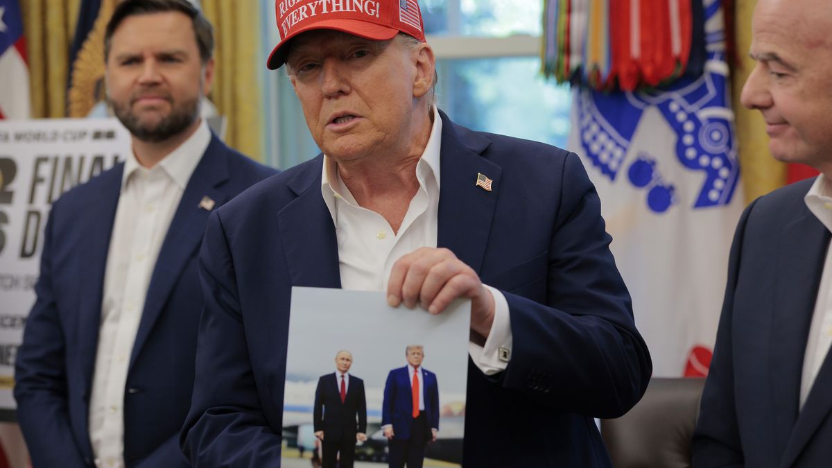 WASHINGTON, DC - AUGUST 22:   U.S. President Donald Trump holds a photograph of him with Russian President Vladimir Putin in Alaska in the Oval Office August 22, 2025 in Washington, DC.  Trump announced the FIFA World Cup 2026 draw will take place at The Kennedy Center.   (Photo by Chip Somodevilla/Getty Images)