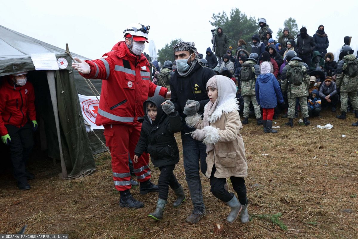 Członkowie Białoruskiego Czerwonego Krzyża wskazują drogę migrantom podczas dystrybucji pomocy humanitarnej w obozie w pobliżu granicy białorusko-polskiej w obwodzie grodzieńskim 14.11.2021 r