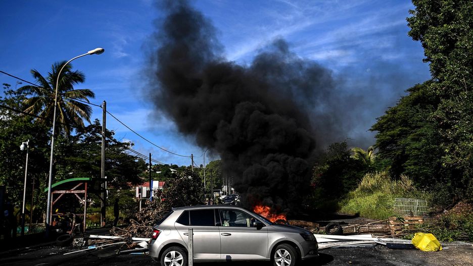 arch48TOPSHOT - A driver does a U-turn at a filtering roadblock made of debris in Le Gosier outside Pointe-a-Pitre on the French Caribbean island of Guadeloupe on November 23, 2021. (Photo by Christophe ARCHAMBAULT / AFP)CHRISTOPHE ARCHAMBAULT