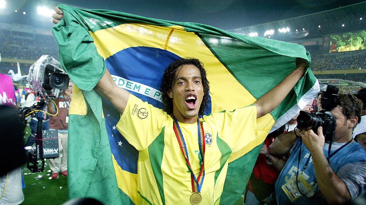 YOKOHAMA, JAPAN - June 30: Ronaldinho of Brazil wearing medal celebrates with flag after winning the FIFA World Cup Final Match 2002 match between Germany and Brazil at International Stadium Yokohama on June 30, 2002 in Yokohama, Japan. (Photo by Richard Sellers/Sportsphoto/Allstar via Getty Images)