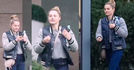 Małgorzata Socha wpatruje się w telefon pod kliniką medycyny estetycznej
