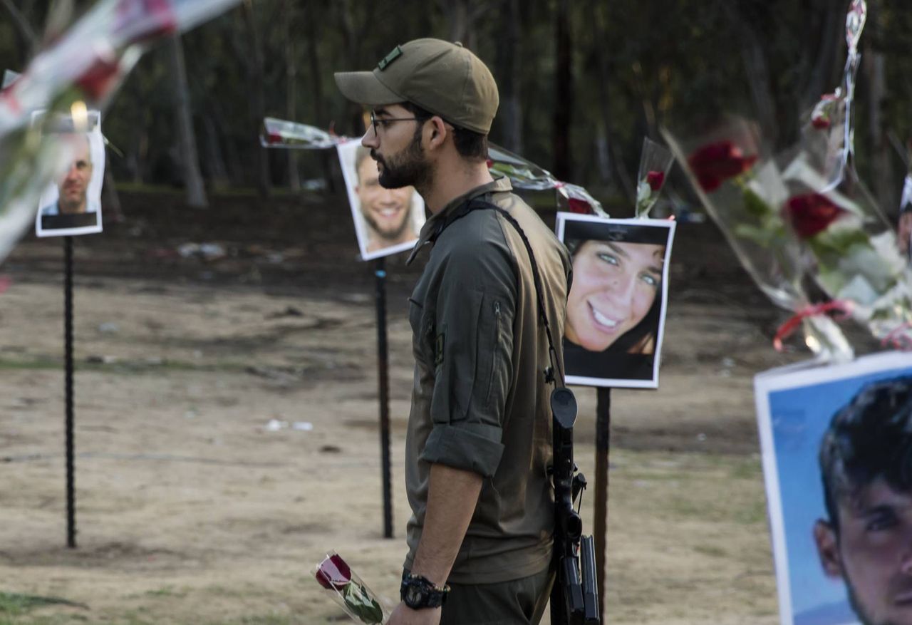 Mężczyzna składający kwiaty w miejscu upamiętniającym ofiary terrorystów z Hamasu