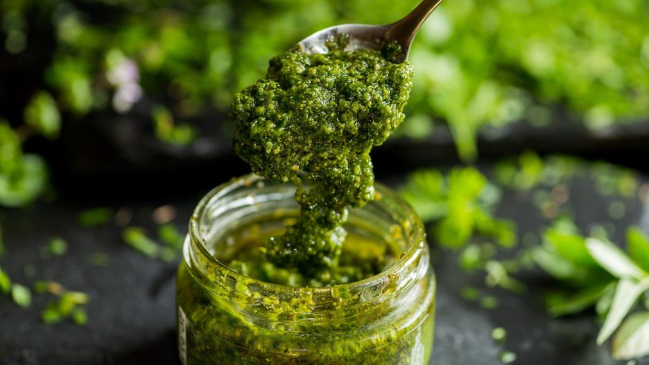 pesto sauce in a spoon, jar with pesto sauce