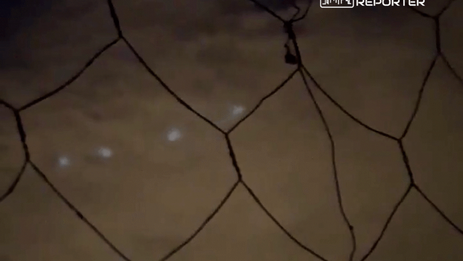 Słabe oświetlenie ukazuje siatkę, za którą widać niejasne, rozmyte światła.