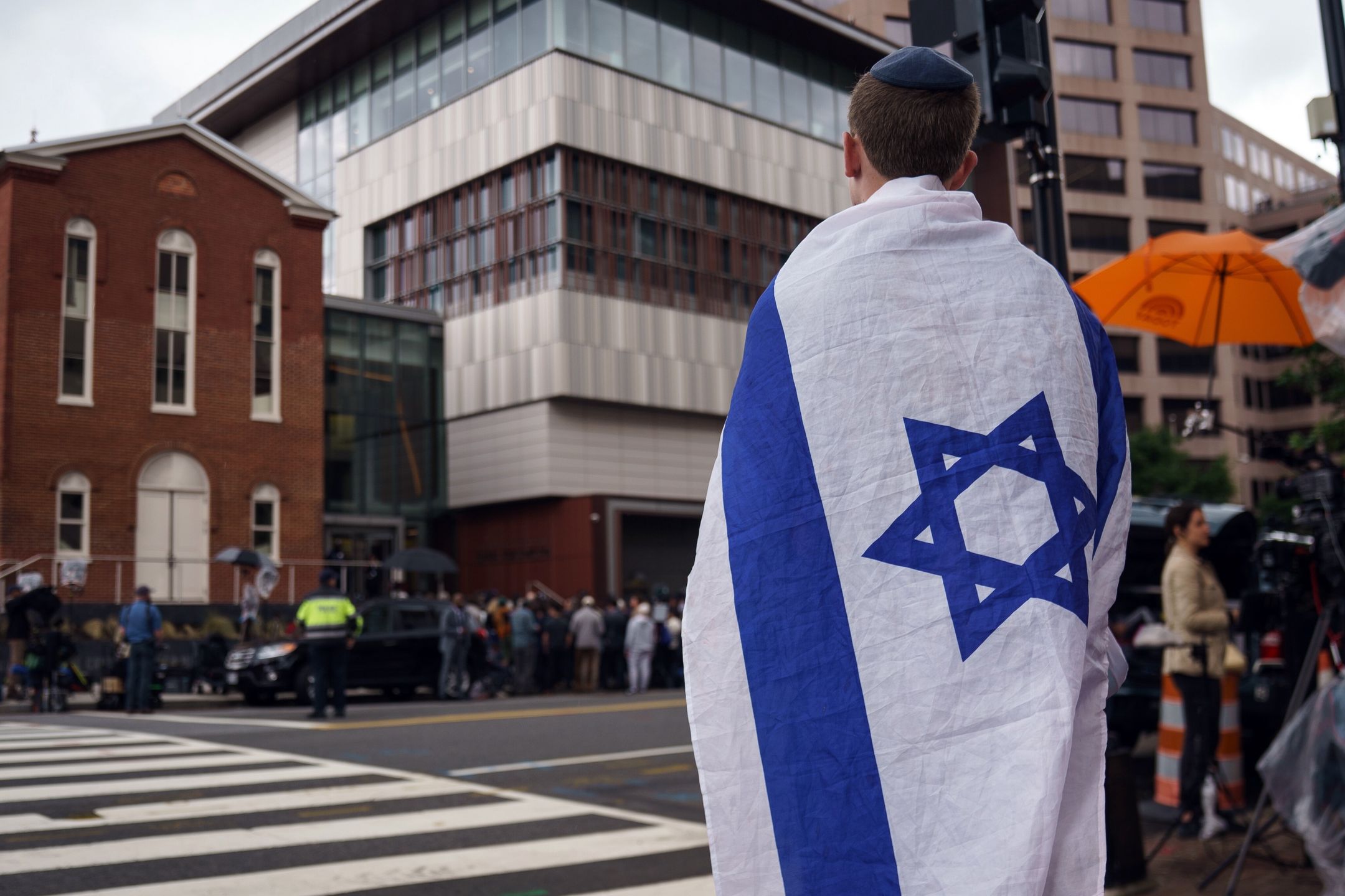 A member of the public with the Israeli flag draped over the shoulders stands close to the scene where two people were shot and killed at the Capital Jewish Museum in Washington, DC, USA, 22 May 2025. According to a social media post by the US Homeland Security Secretary Kristi L. Noem, the two people killed last night were staff members at the Israeli embassy. EPA/WILL OLIVER Dostawca: PAP/EPA.