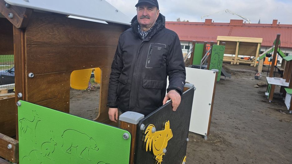 Wójt Jerzy Lewi Kiedrowski przy placu zabaw wykonanym z drewna rubinowego