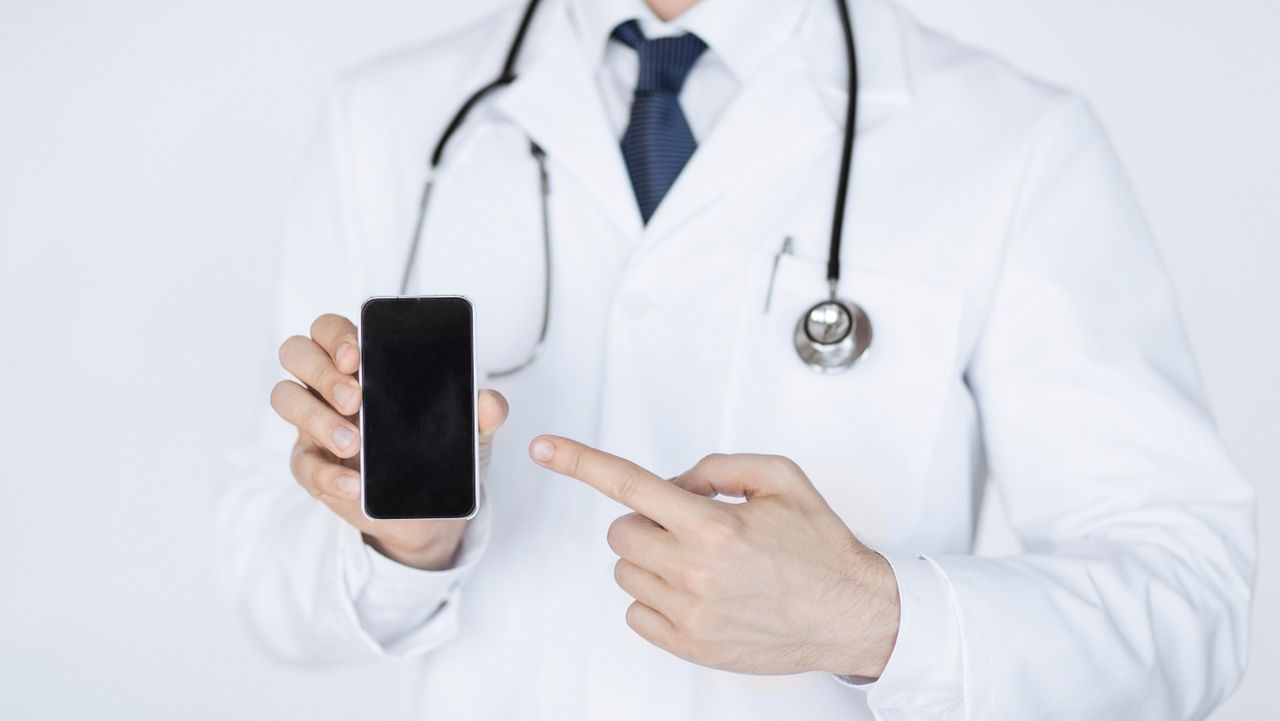 close up of male doctor pointing at smartphone