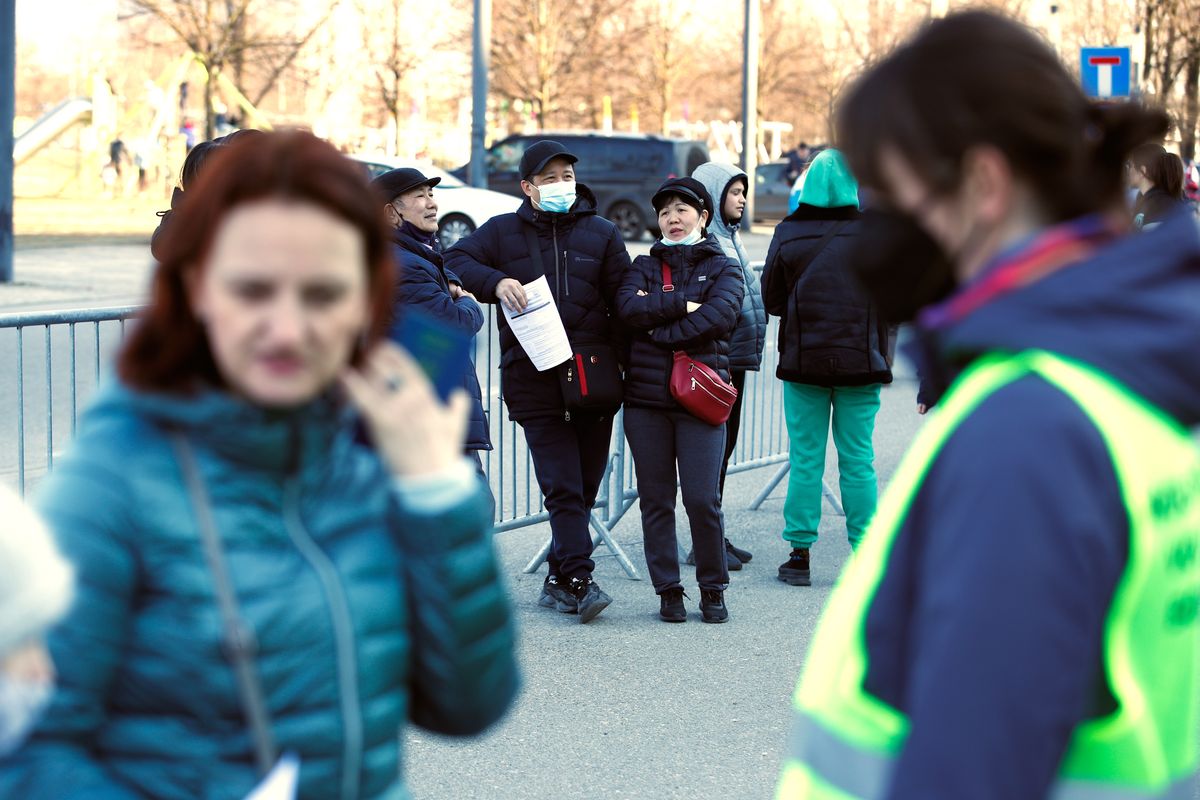 People are seen waiting outside the National Stadium to register for a Polish social security number in Warsaw, Poland on 19 March, 2022. The Polish government is trying to fasttrack refugees from Ukraine into employment by adjusting laws that will allow for them to apply to a PESEL, a social security number. Hundreds stood in line to register in the early morning on Saturday. Because of the large number of applicants the office shut down early. (Photo by STR/NurPhoto via Getty Images)