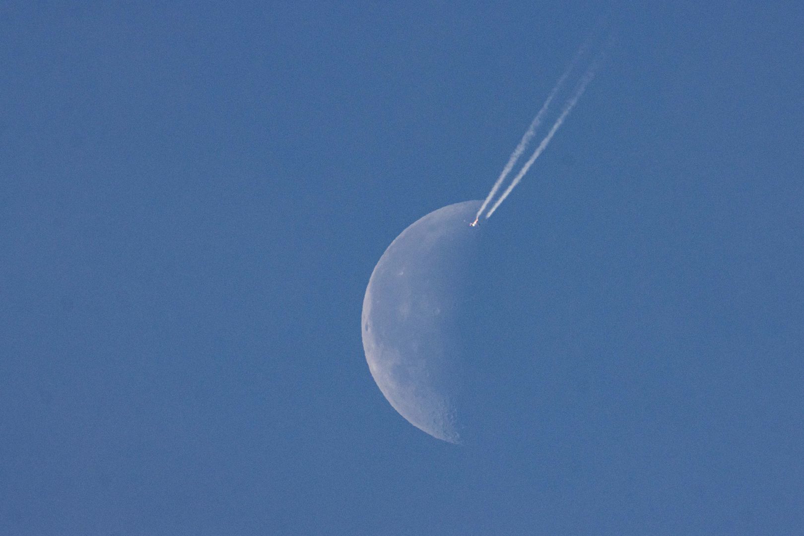 A passenger plane is cruising at 40.000 feet altitude and passing in front of the half moon, on a cloudless sunny spring day as the aircraft is flying over Europe in the Dutch sky. Moonpass is the ultimate goal of aviation photographers, the planespotters. During the flight, the passenger jet is leaving behind contrails or condensation trail, a white vapor line as it passes in front of Earth's natural satellite and closest celestial object in the universe. Eindhoven, The Netherlands on April 24, 2022. (Photo by Nicolas Economou/NurPhoto via Getty Images)
