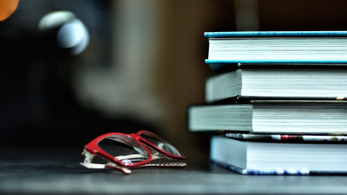 Książki w sztywnych okładkach i czerwone okulary do czytania