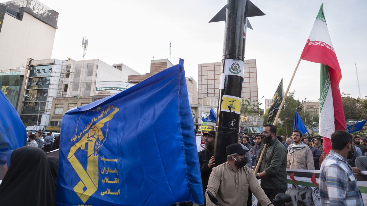 Veiled women are waving an Iranian flag and a flag of the Islamic Revolutionary Guard Corps while two unidentified men are carrying a model of Iran's first-ever hypersonic missile, Fattah, during a gathering to celebrate the IRGC UAV and missile attack against Israel, at Palestine Square in downtown Tehran, Iran, on April 15, 2024. Iran launched dozens of Unmanned Aerial Vehicles (UAVs) and missiles against Israel on April 13th in response to the Israeli attack on its Consulate in Damascus. (Photo by Morteza Nikoubazl/NurPhoto via Getty Images)