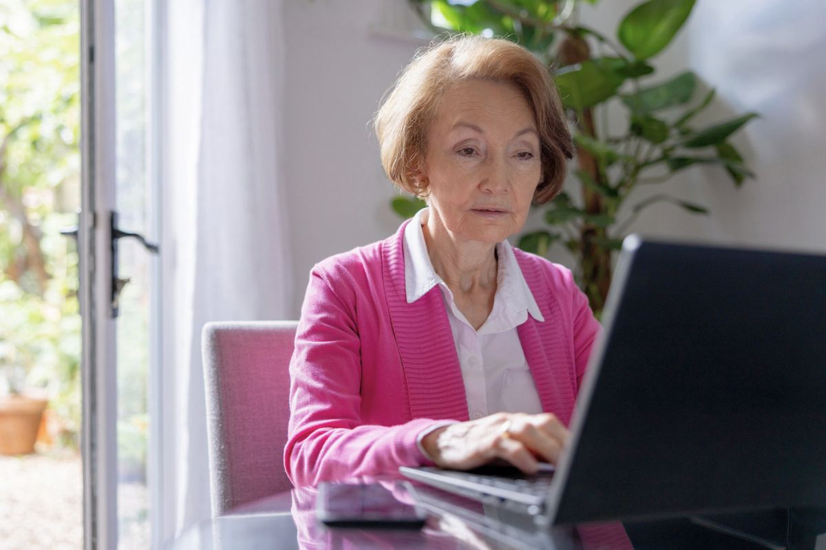 The senior lady is writing on the computer.