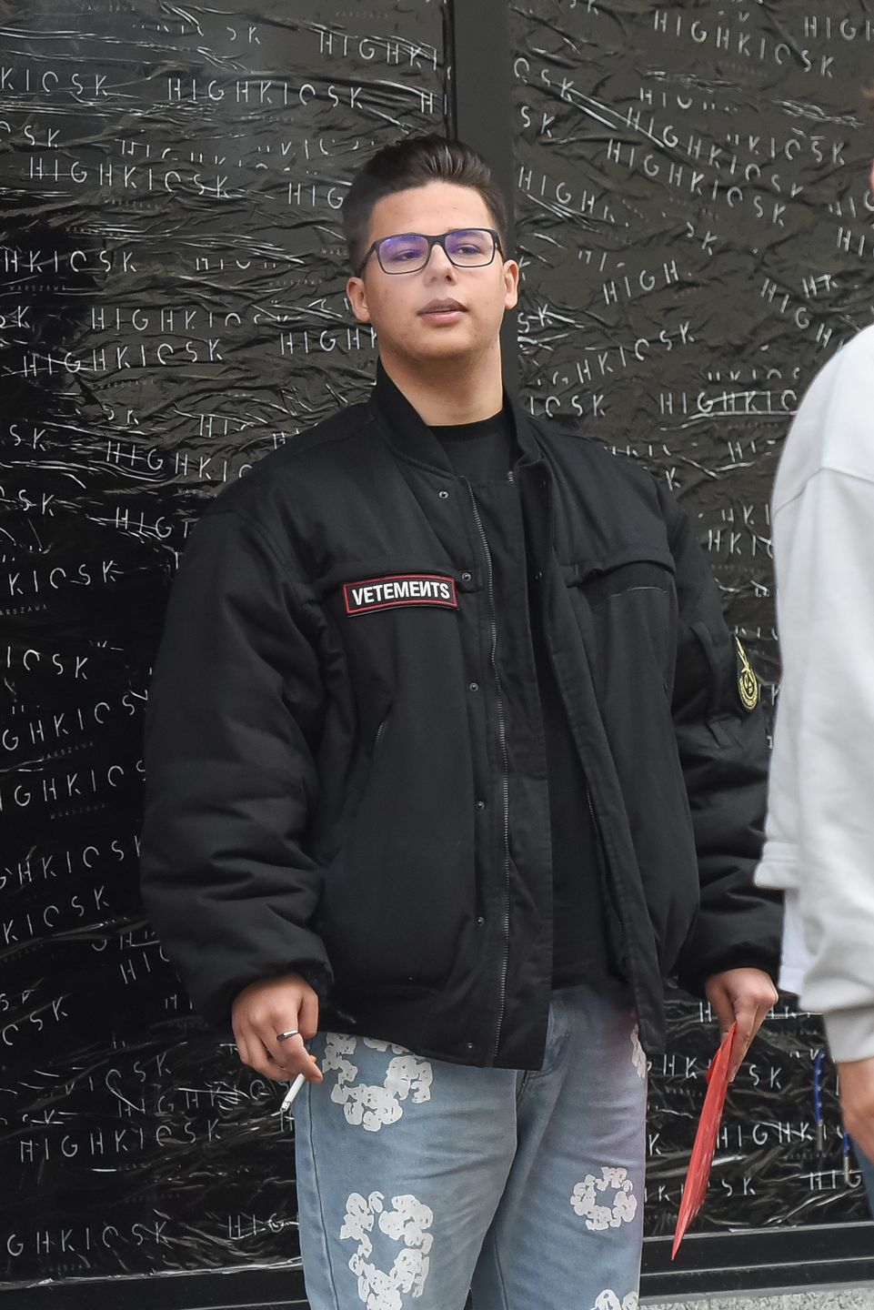 Allan Krupa pali papierosa przed butikiem