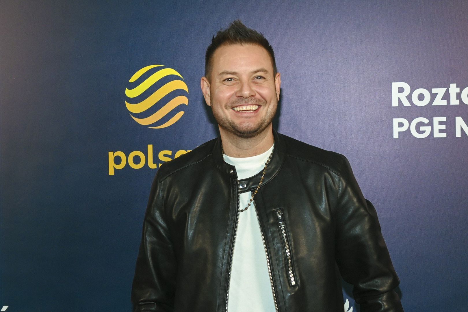 Bartek Wrona, jako najmłodszy członek grupy, szybko zdobył sympatię fanek. Jego młodzieńczy urok i talent wokalny przyciągały tłumy na koncerty Just 5. Zespół wydał jeszcze dwa albumy: &#34;Zaczarowany świat&#34; w 1998 roku oraz &#34;Cień wielkich miast&#34; w 2001 roku, zanim zakończył działalność w 2002 roku.Na zdjęciu Bartek Wrona na imprezie Roztańczony PGE Narodowy. Rok 2024.