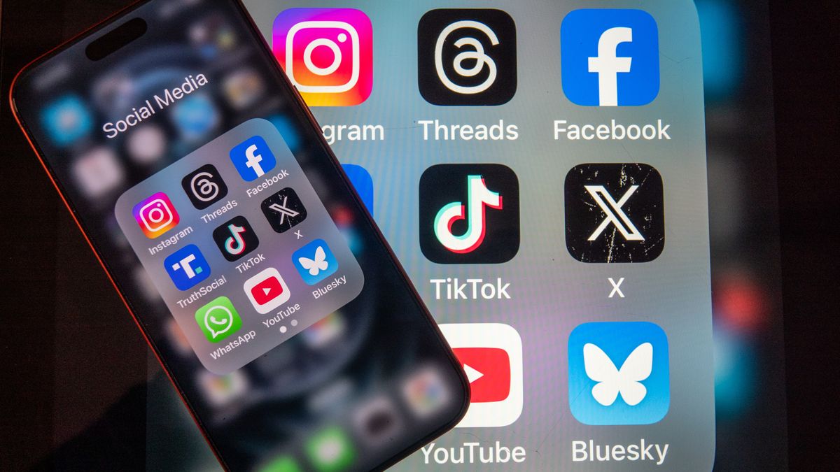 BATH, UNITED KINGDOM - FEBRUARY 08: In this photo illustration a man holds an iPhone screen displaying various social media and messaging apps on February 8, 2026 in Bath, England. On top row left to right, the logo of social media platform Instagram is seen beside that of Meta’s Threads and Facebook. On the middle row from left is the logo of Donald Trump's Truth Social app, next to the logo of social media app TikTok and the logo of Elon Musk’s US online social media and social networking site 'X' (formerly known as Twitter). Along the bottom row, left to right is the messaging service WhatsApp, the logo for online video sharing and social media platform YouTube and the logo for the Bluesky app. In the UK, a ban on social media for under-16s has been backed by the House of Lords following the Australian law which aims to stop children under 16 from having social media accounts and social media platforms, including TikTok, Facebook, Snapchat, Reddit, X, formerly Twitter, and Instagram potentially being be fined for preventing children younger than 16 from having social media accounts. (Photo by Anna Barclay/Getty Images)