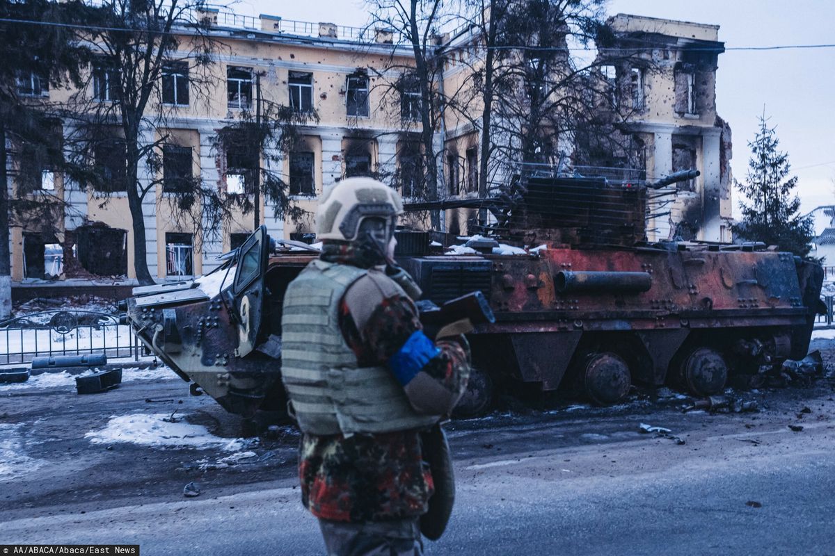 Wojna w Ukrainie. Ukraiński żołnierz przechodzi obok zniszczonego, rosyjskiego czołgu w Charkowie 