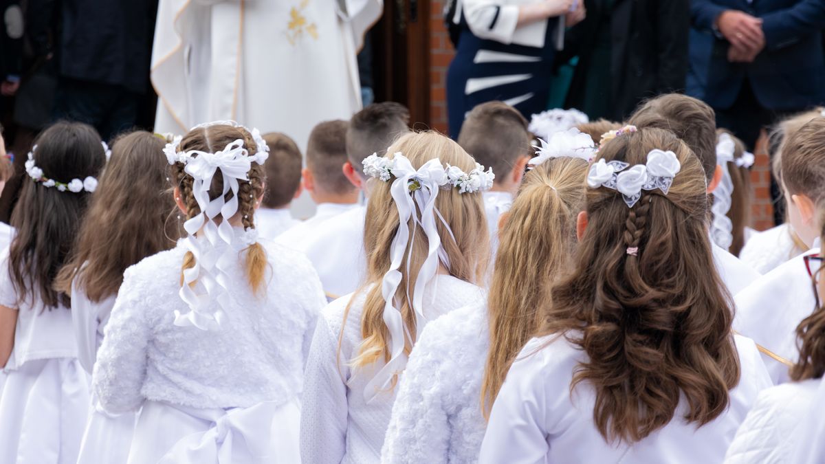 A group of children in solemn white clothes is waiting in front of the entrance to the church. Preparation for the first Holy Communion and for the Holy Mass.communion, religion, sacrament, christian, catholicism, church, christ, christianity, cross, uniform, spiritual, symbol, ceremony, child, people, white, god, young, easter, holy, childhood, catholic, bible, prayer, kid, tunic, boy, wood, religious, crucifix, pray, jesus, faith, rosary, celebration, believe, person, dress, beautiful, first, kids, cheerful, beauty, shoes, follower, girl, mass, liturgy, liturgical, latin girl