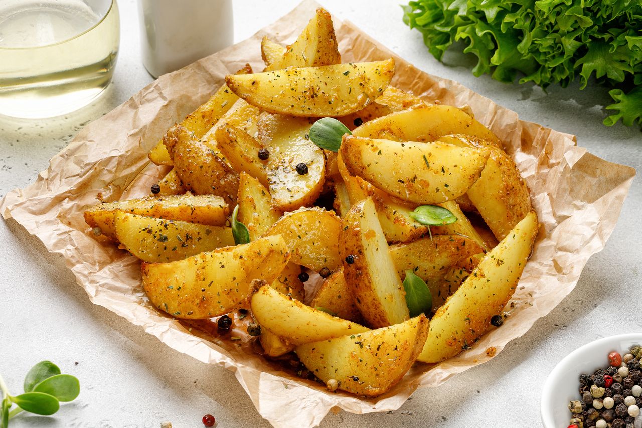 Baked potato wedges on craft paper. Roasted potatoes with herbs and spices. Dinner idea.
Maria TEBRYAEVA
