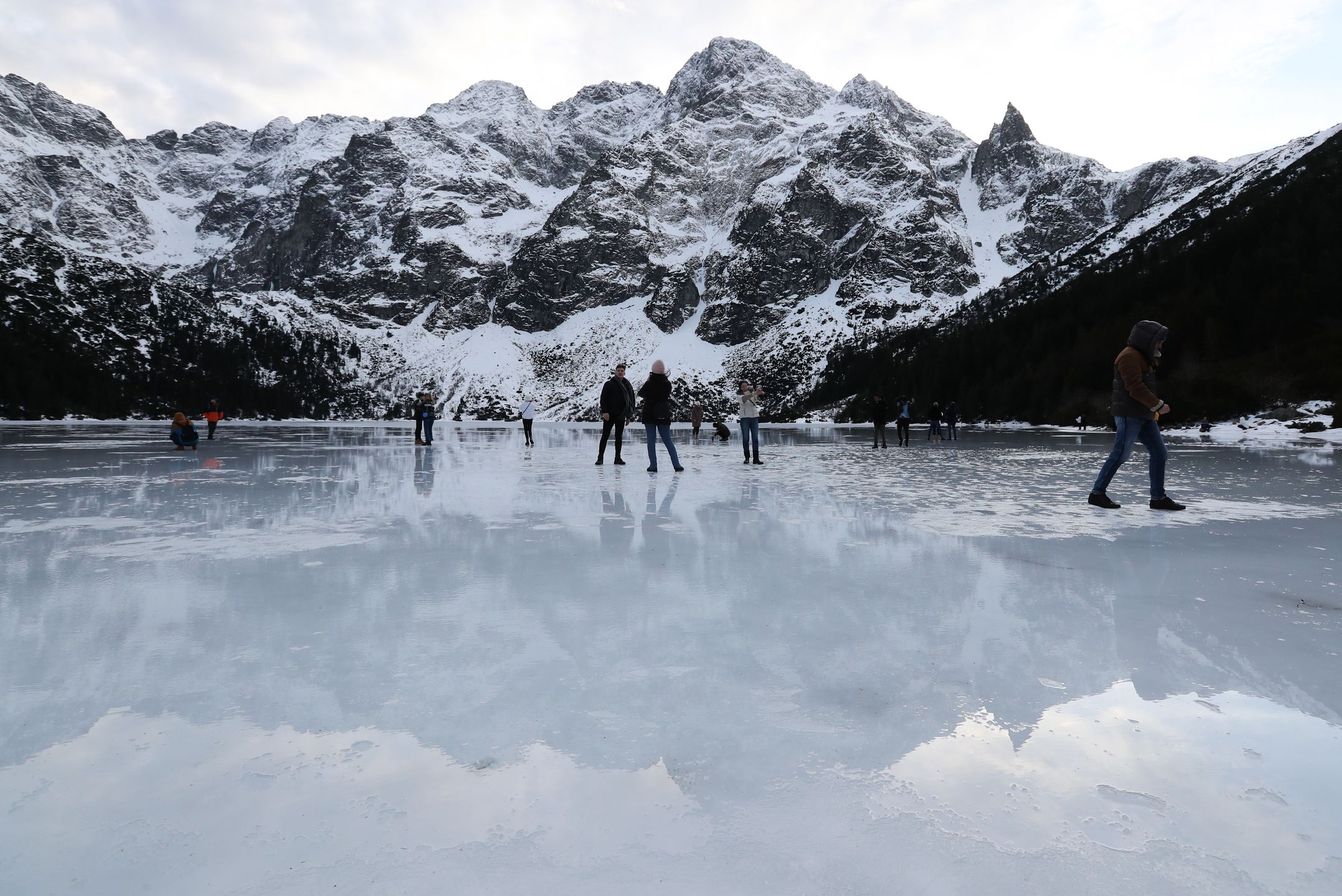 Tatry, Morskie Oko, 26.12.2022. Turyści na tafli lodu na jeziorze Morskie Oko w Tatrach, 26 bm. Tatrzański Park Narodowy ostrzega przed wchodzeniem na zamarznięte górskie jeziora � z powodu panujących w ciągu dnia dodatnich temperatur lód jest bardzo cienki i grozi załamaniem. (jm) PAP/Grzegorz Momot