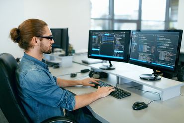 Na zdjęciu programista przed komputerem