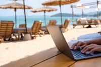 Na zdjęciu osoba na laptopie na plaży
