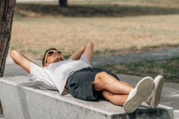 Na zdjęciu mężczyzna leżący na murze w okularach przeciwsłonecznych