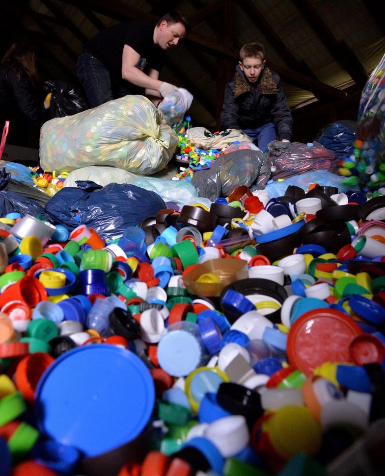Wolontariusze krakowskiej fundacji "Bez Tajemnic" segregują i przepakowują plastikowe zakrętki w magazynie w Krakowie