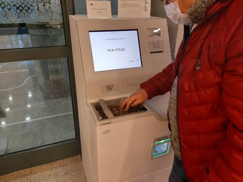Automat wymienia monety na banknoty. Ludzie ustawiają się w kolejkach