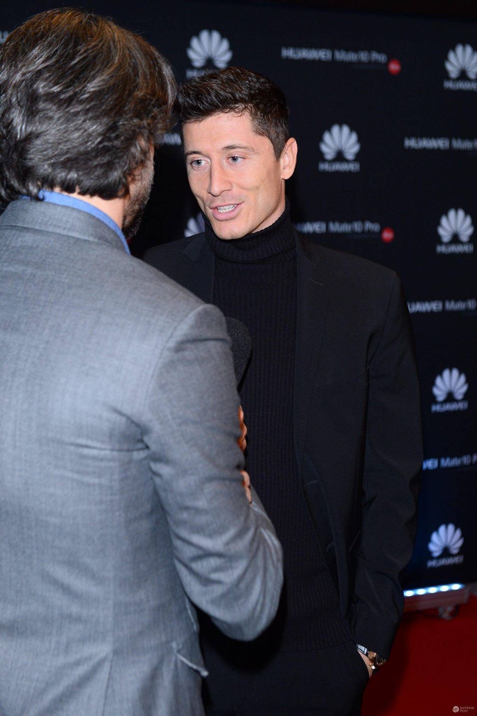 Robert Lewandowski w czarnym garniturze i golfie promuje telefon komórkowy, 2017