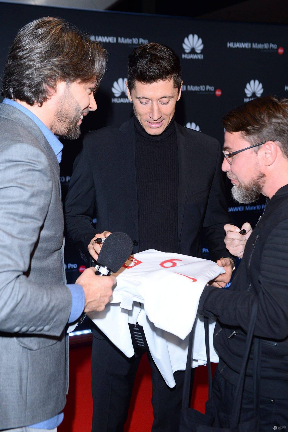 Robert Lewandowski w czarnym garniturze i golfie promuje telefon komórkowy, 2017