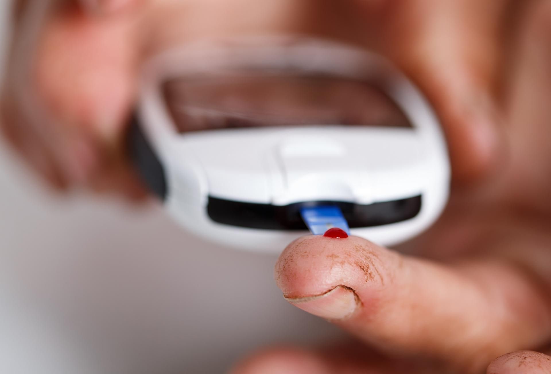 Osoba chora na cukrzycę bada poziom glikemii za pomocą glukometru. 