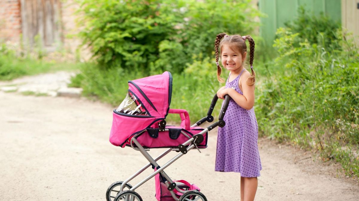 Dziewczynka bawi się lalką w wózku.